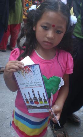 Child at fair in Nepal holding CEPHED lead paint flyer