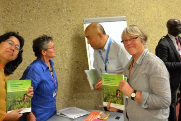 Rossana Dewi (Gita Pertiwi) and Stephanie Williamson (PAN UK) holding copies of PAN's new agroecology book, while Meriel Watts speaks with an event attendee in the background